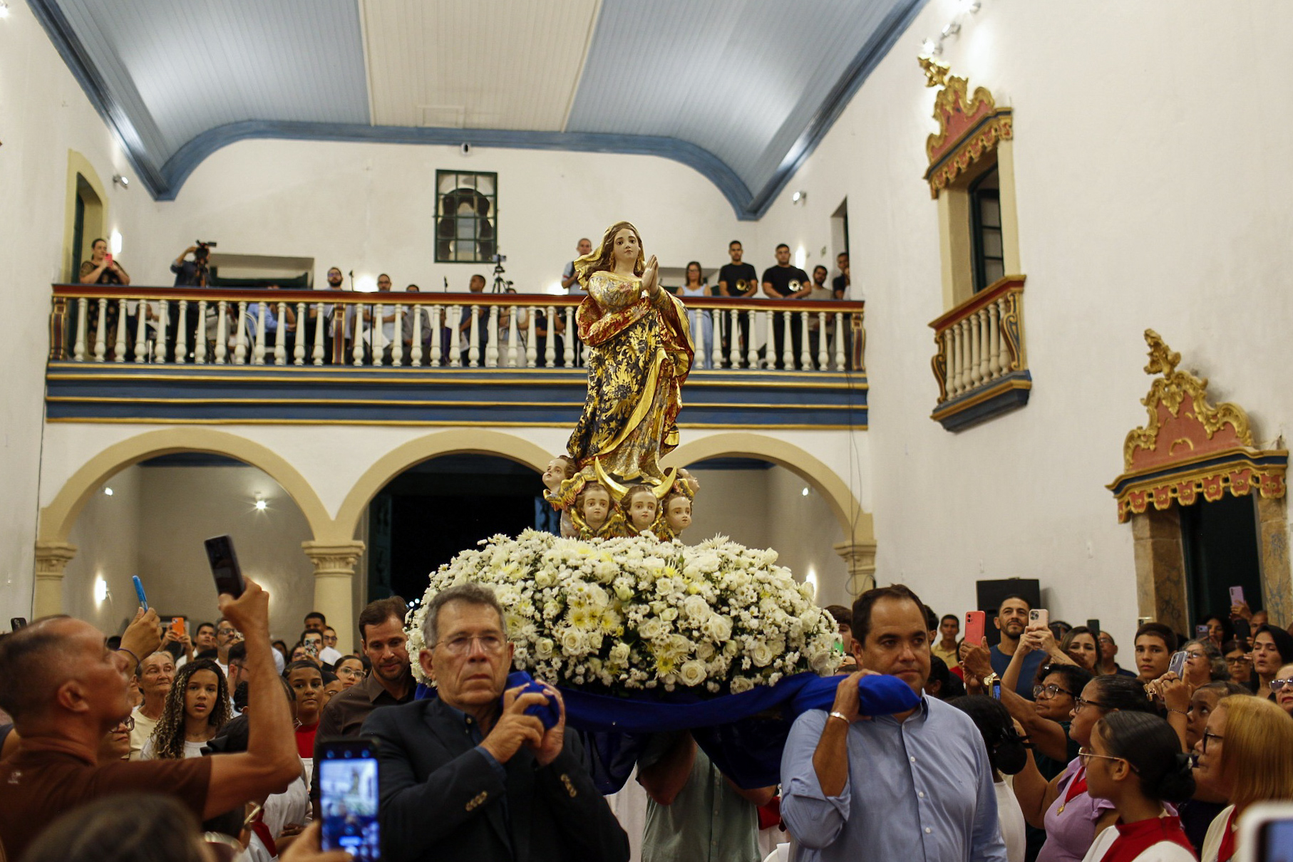 Pessoas em procissão com a imagem de uma santa