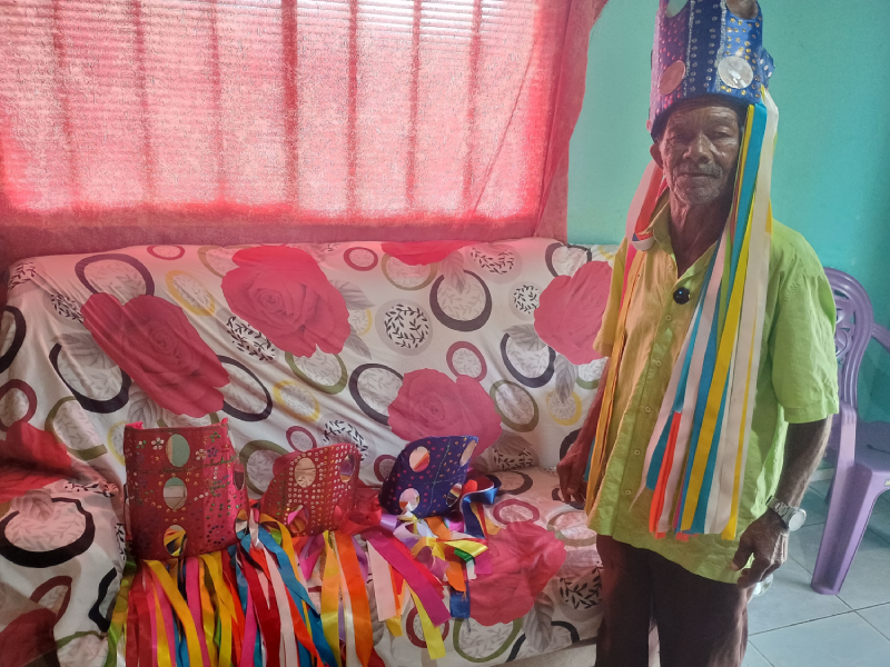 Homem em frente a uma sofá mostra chapéus coloridos