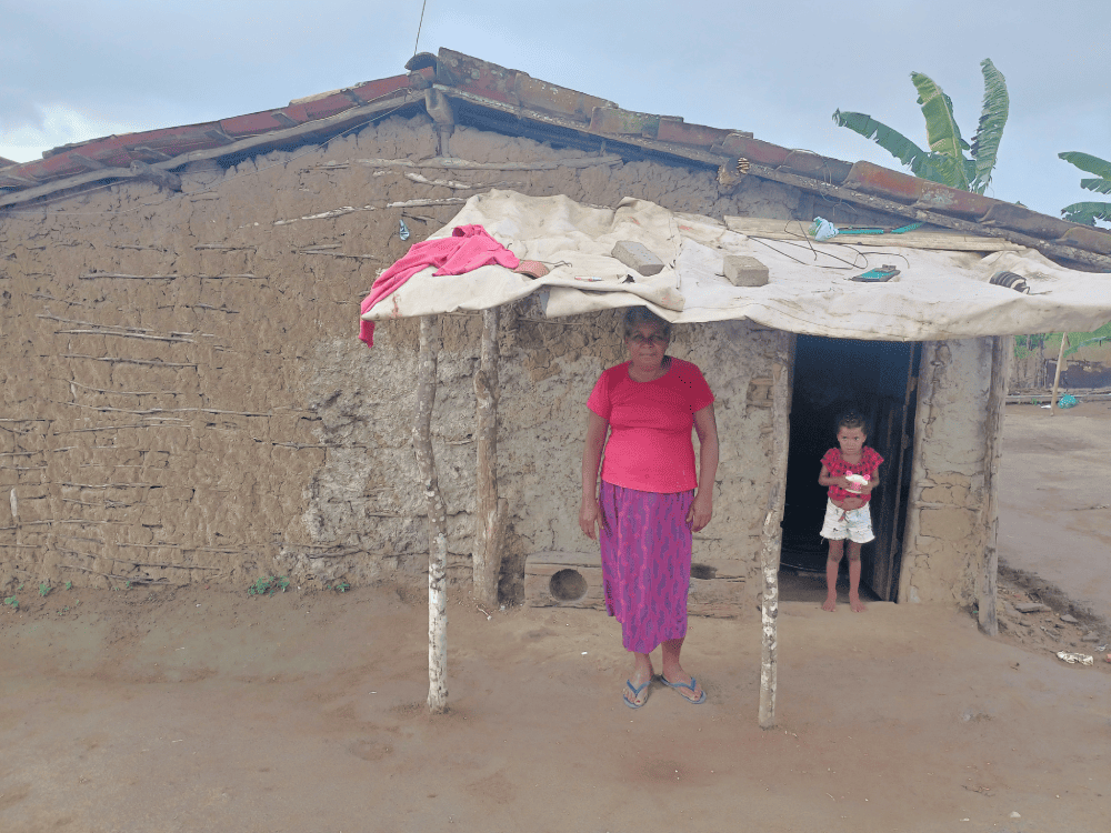 Mulher e criança em frente a uma casa