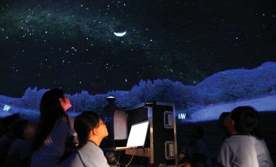 Grupo escolar observando o céu na cúpula do planetário