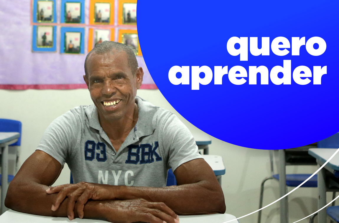 "Homem sorridente sentado em uma sala de aula, com um balão azul ao lado contendo o texto ‘quero aprender’ em branco."