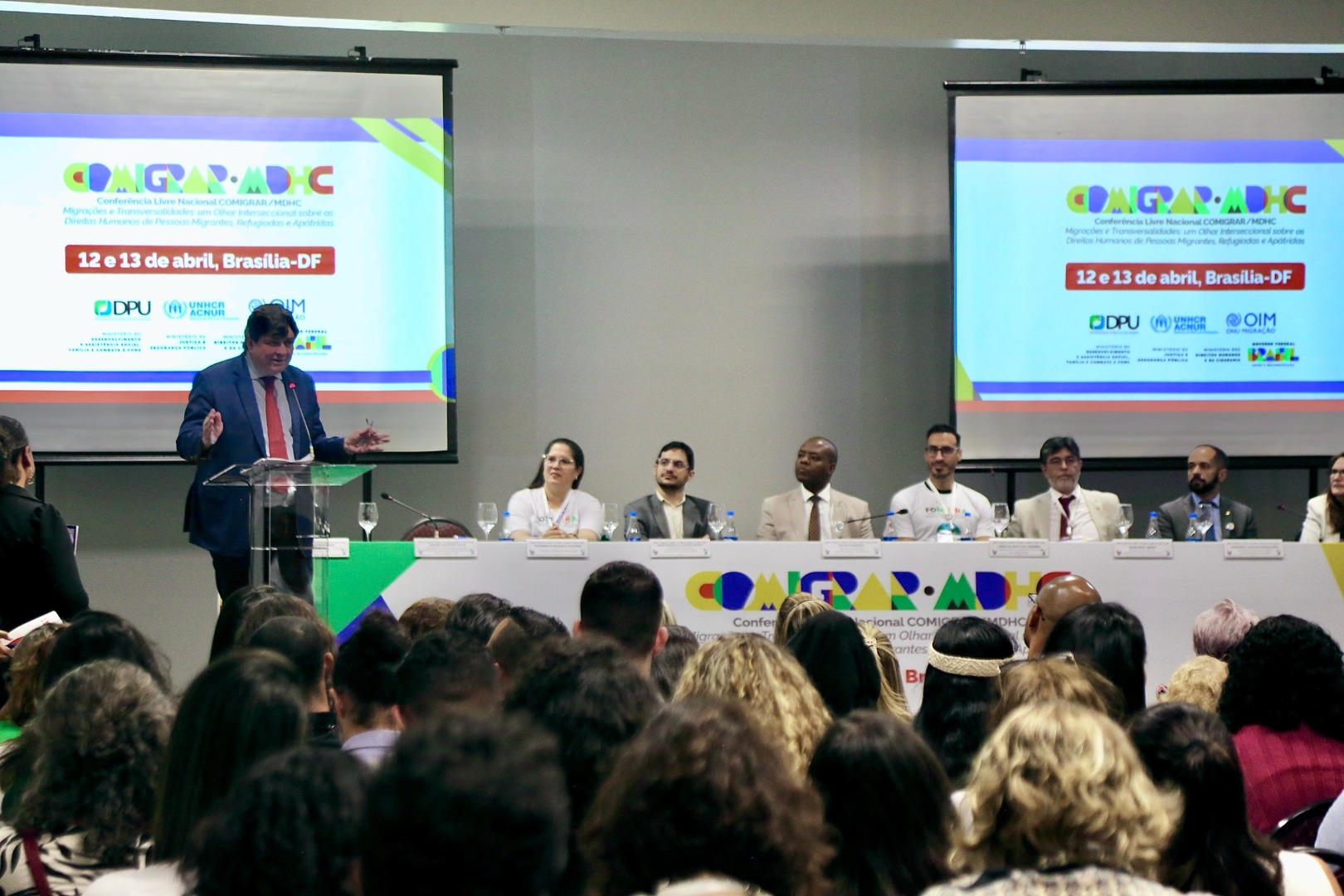 Participação da sociedade civil, ineditismo mundial da iniciativa e vanguarda da legislação brasileira foram pontos destacados durante a abertura da segunda Conferência Livre Nacional de Migrações, Refúgio e Apatridia (Comigrar)
