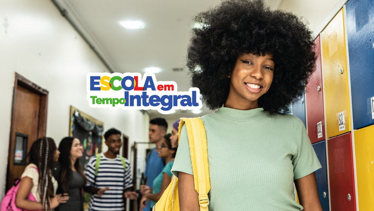Estudante sorridente em corredor escolar com mochila amarela, ao lado de armários coloridos, enquanto outros jovens conversam ao fundo; destaque para o programa Escola em Tempo Integral.