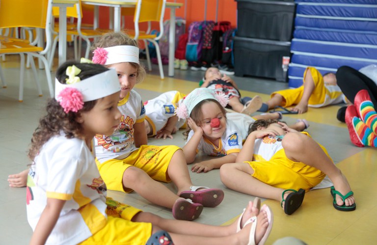 Crianças da educação infantil participam de atividade lúdica no chão da sala de aula, exemplo de práticas voltadas ao desenvolvimento na primeira infância.