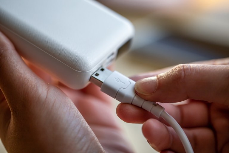 womans-hand-holding-white-usb-cable-and-white-power-bank.jpg