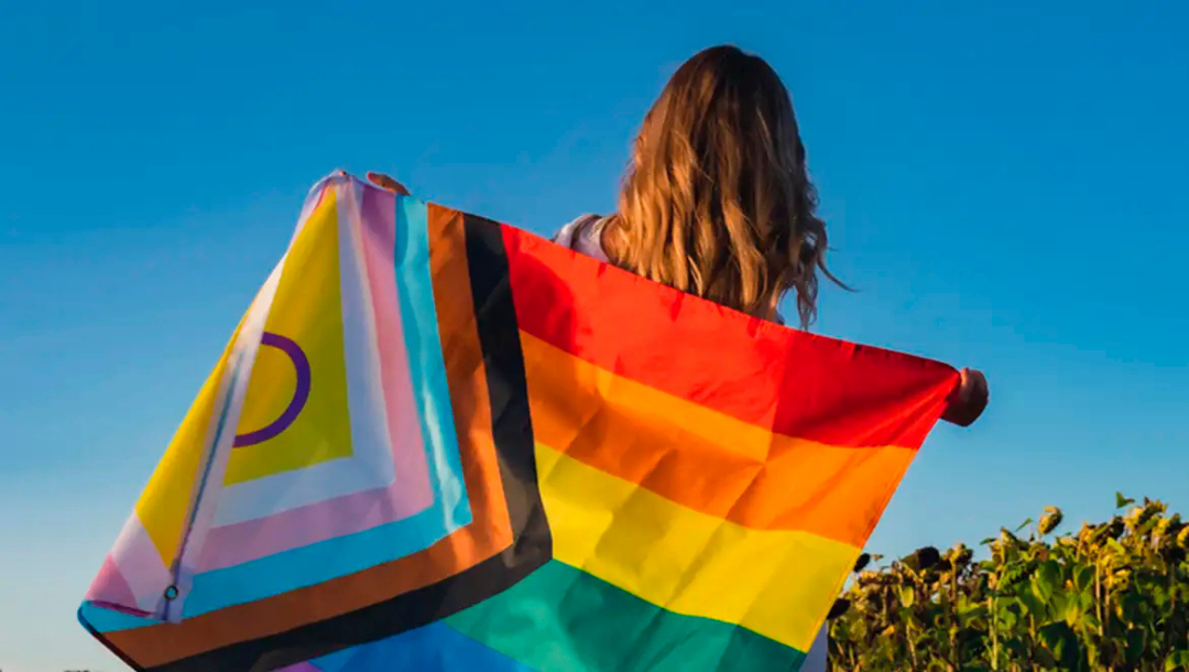 Mulher segurando bandeira do movimento LGBTQIA. Crédito: conflgbtqia.org/Divulgação