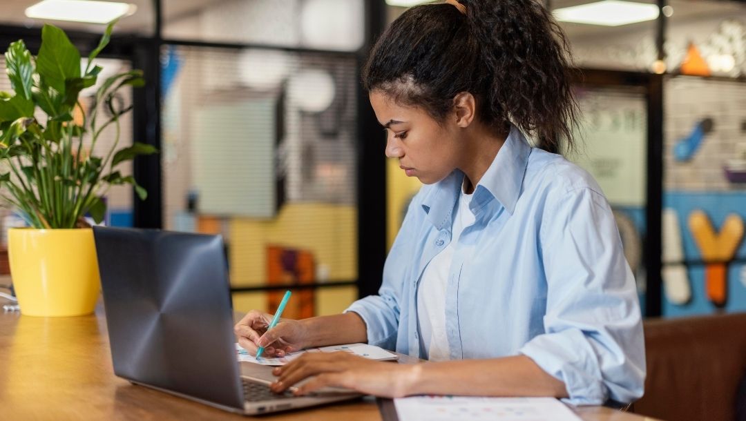Mulher negra fazendo anotações em frente ao computador