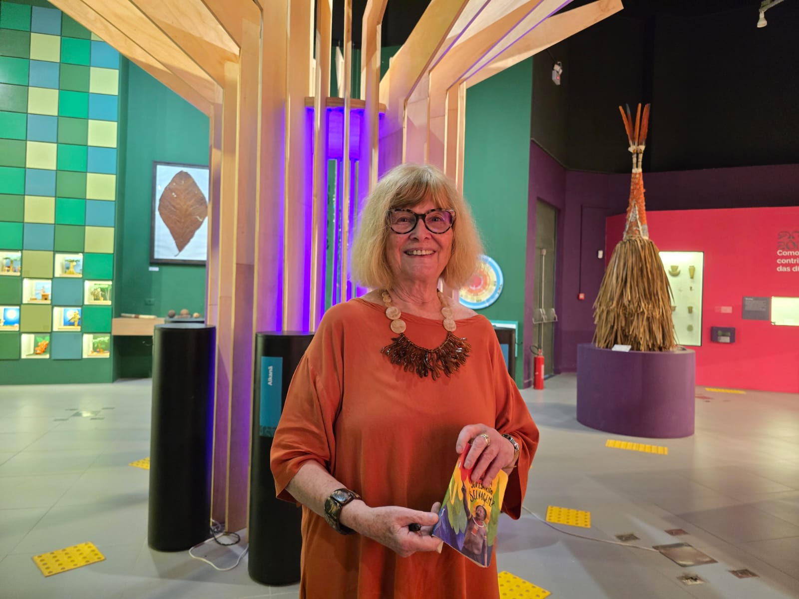 Mulher branca sorrindo em ambiente colorido de museu