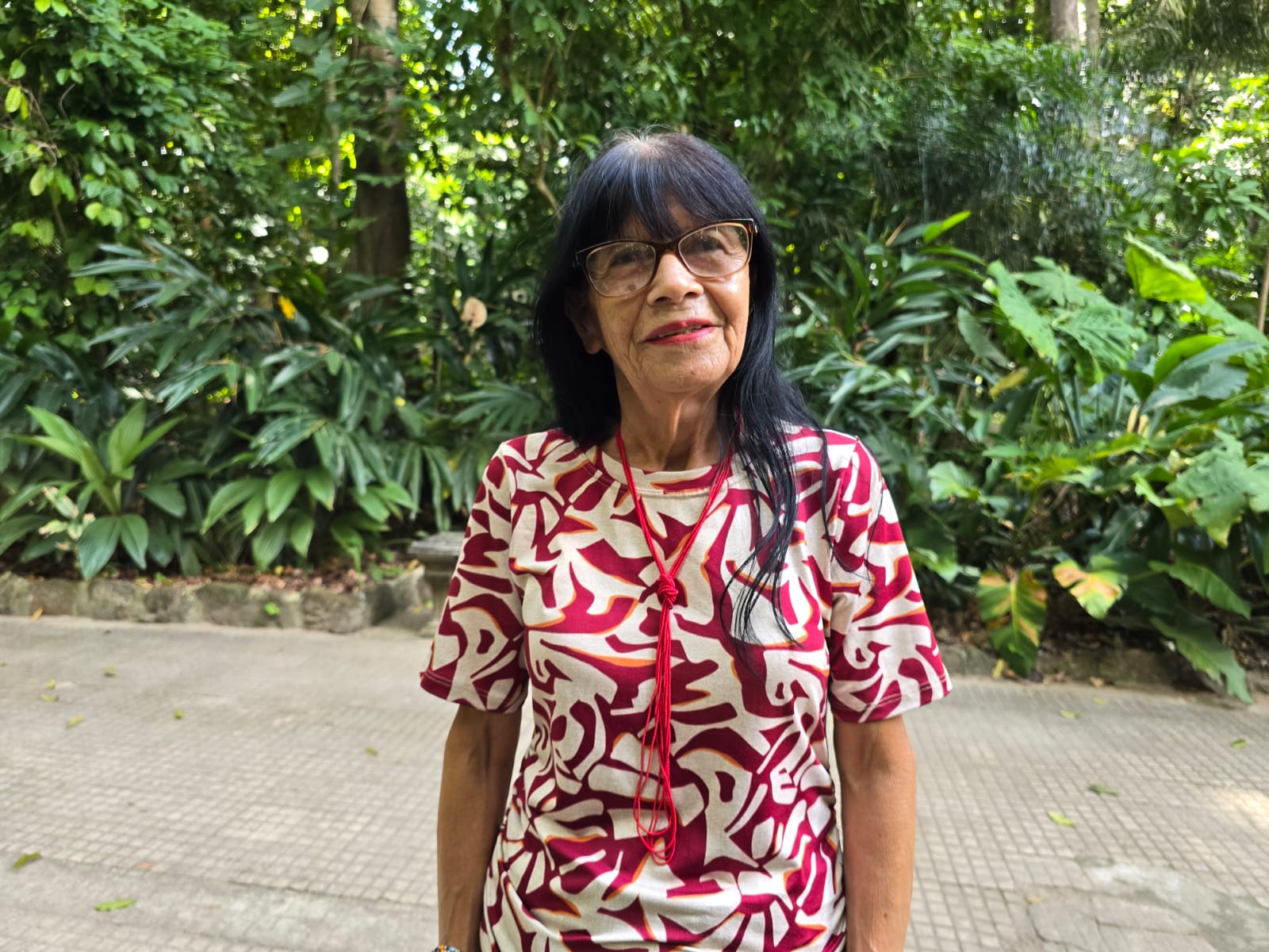 Mulher indígena com roupa e adereços coloridos em um ambiente de parque