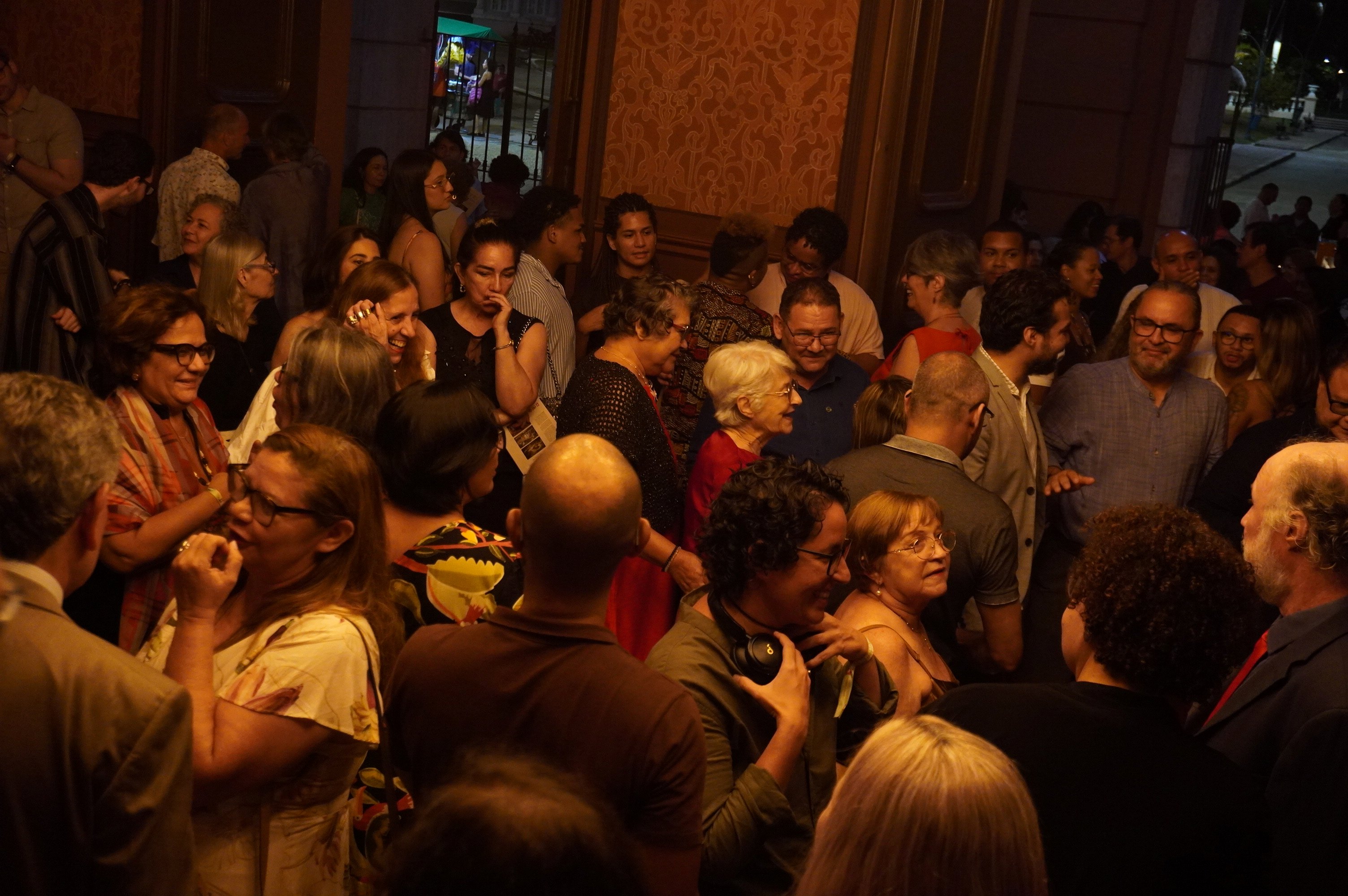 pessoas se confraternizam em hall de teatro