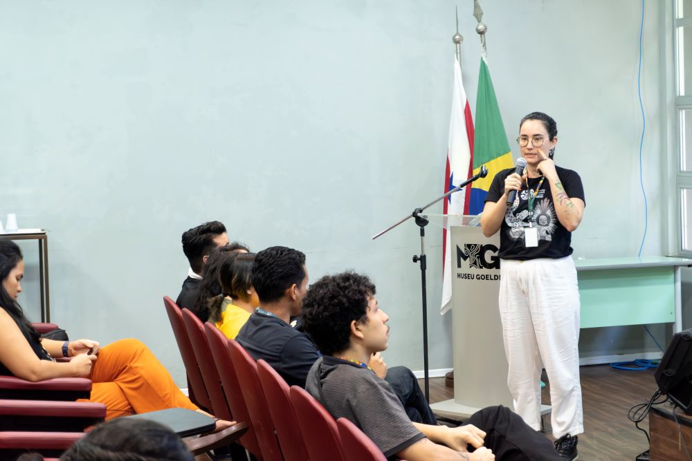 Mulher segurando microfone fala a pessoas em um auditório