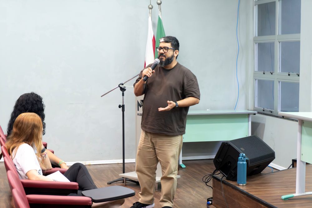 Homem em pé fala a plateia em auditório