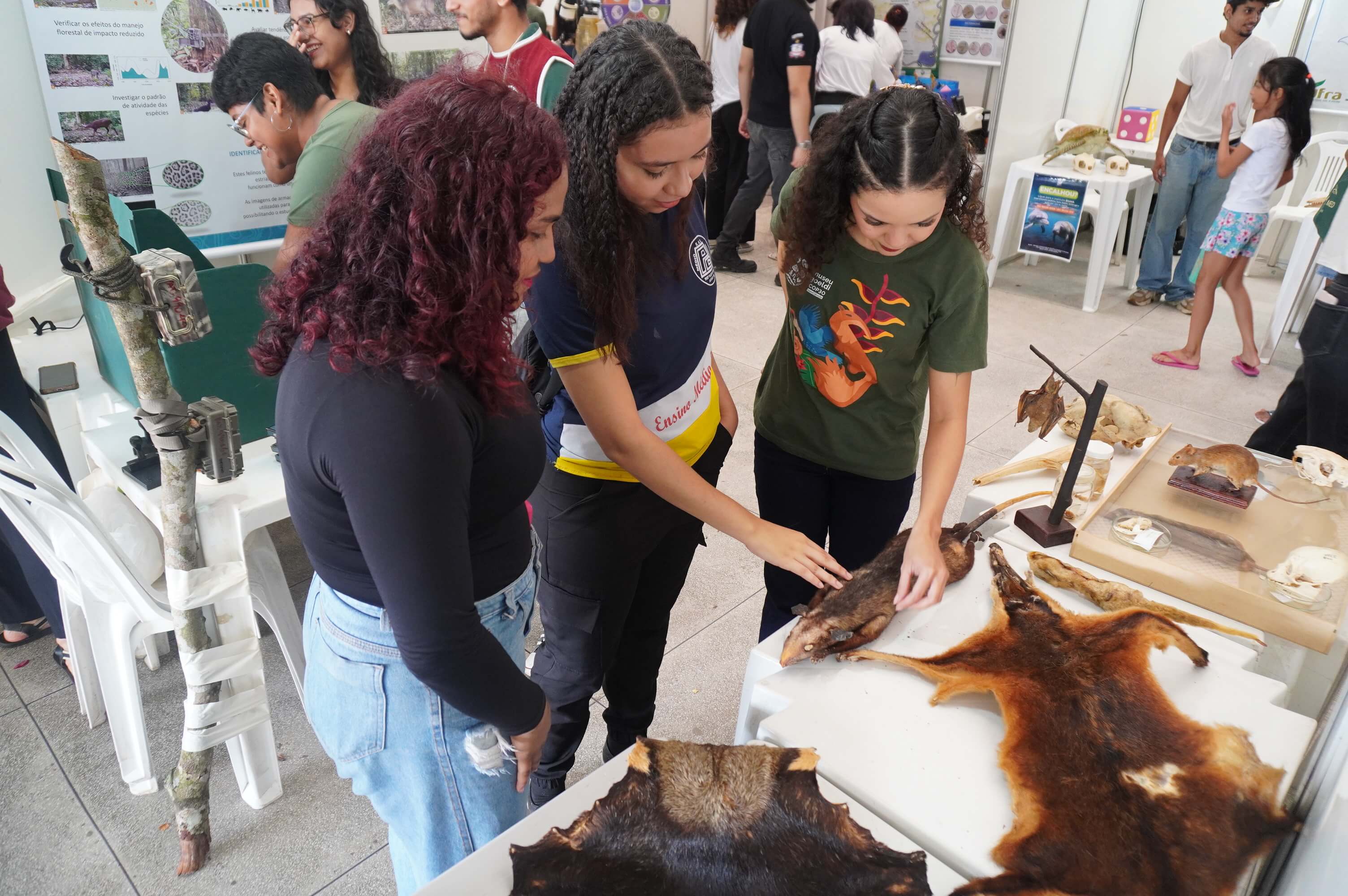 Mulheres tocam em peles de animais expostyas numa feira de ciências