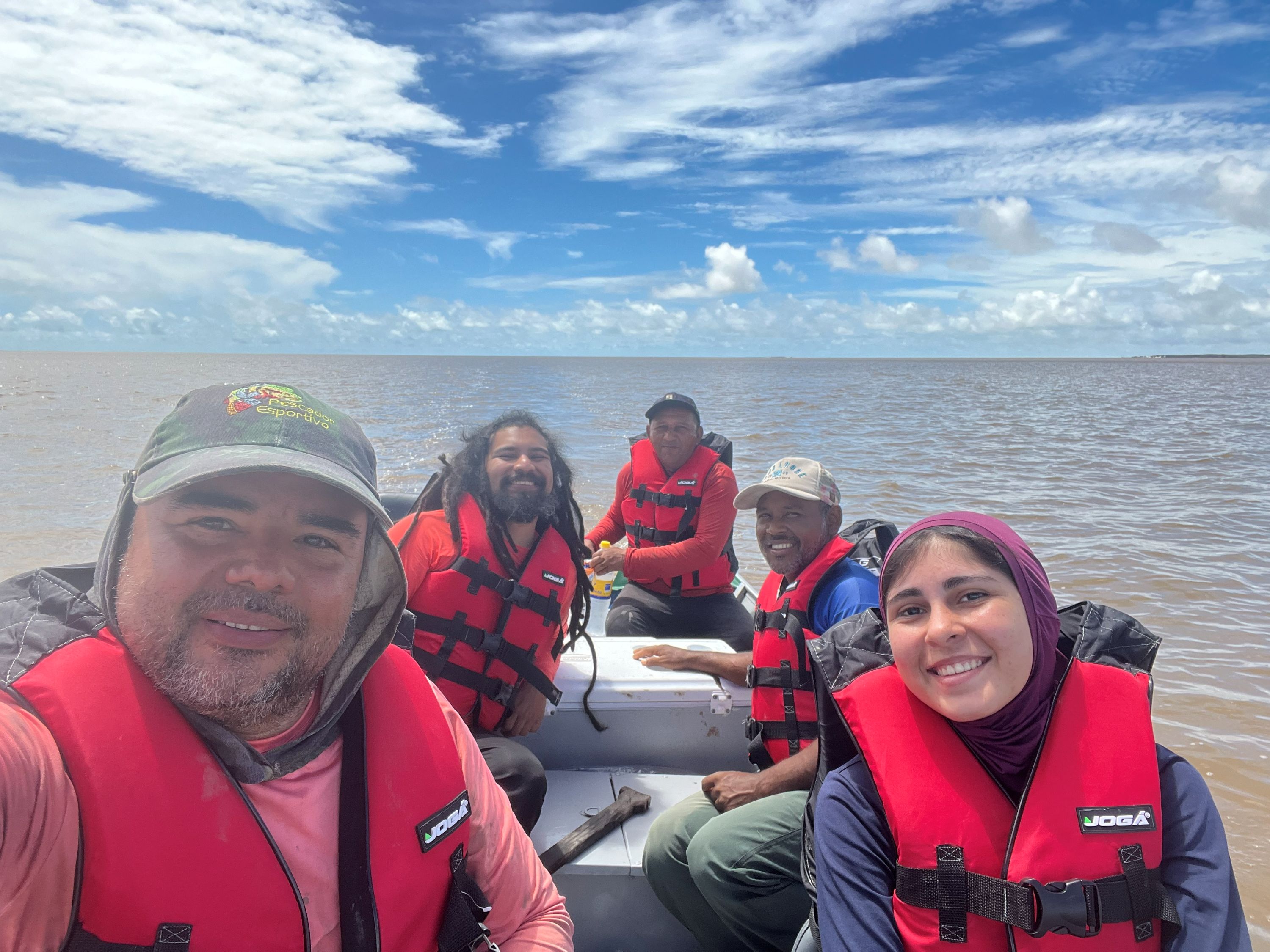Quatro homens e uma mulher posam para selfie dentro de barco