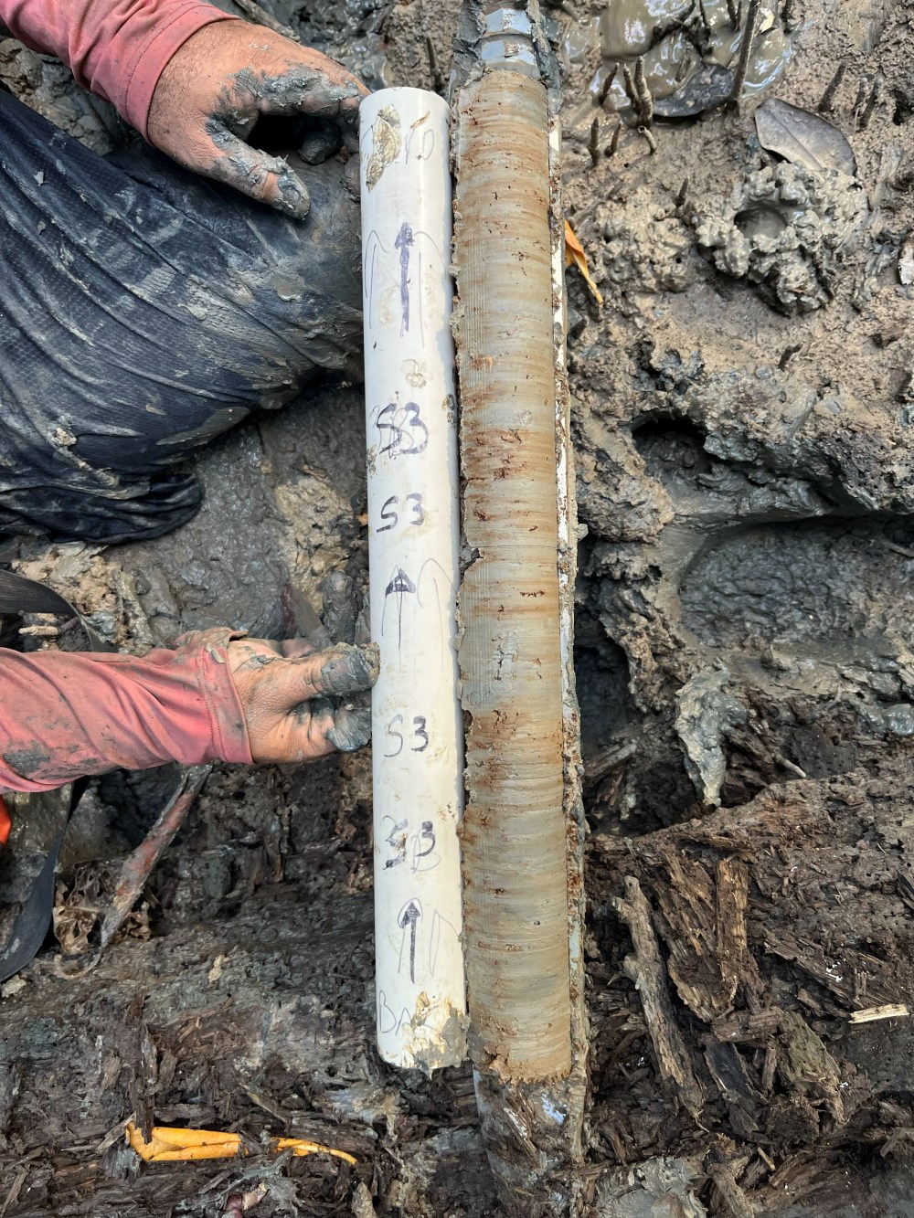 foto mostra um cano de pvc e um trado, objeto de metal com faixas oxidadas
