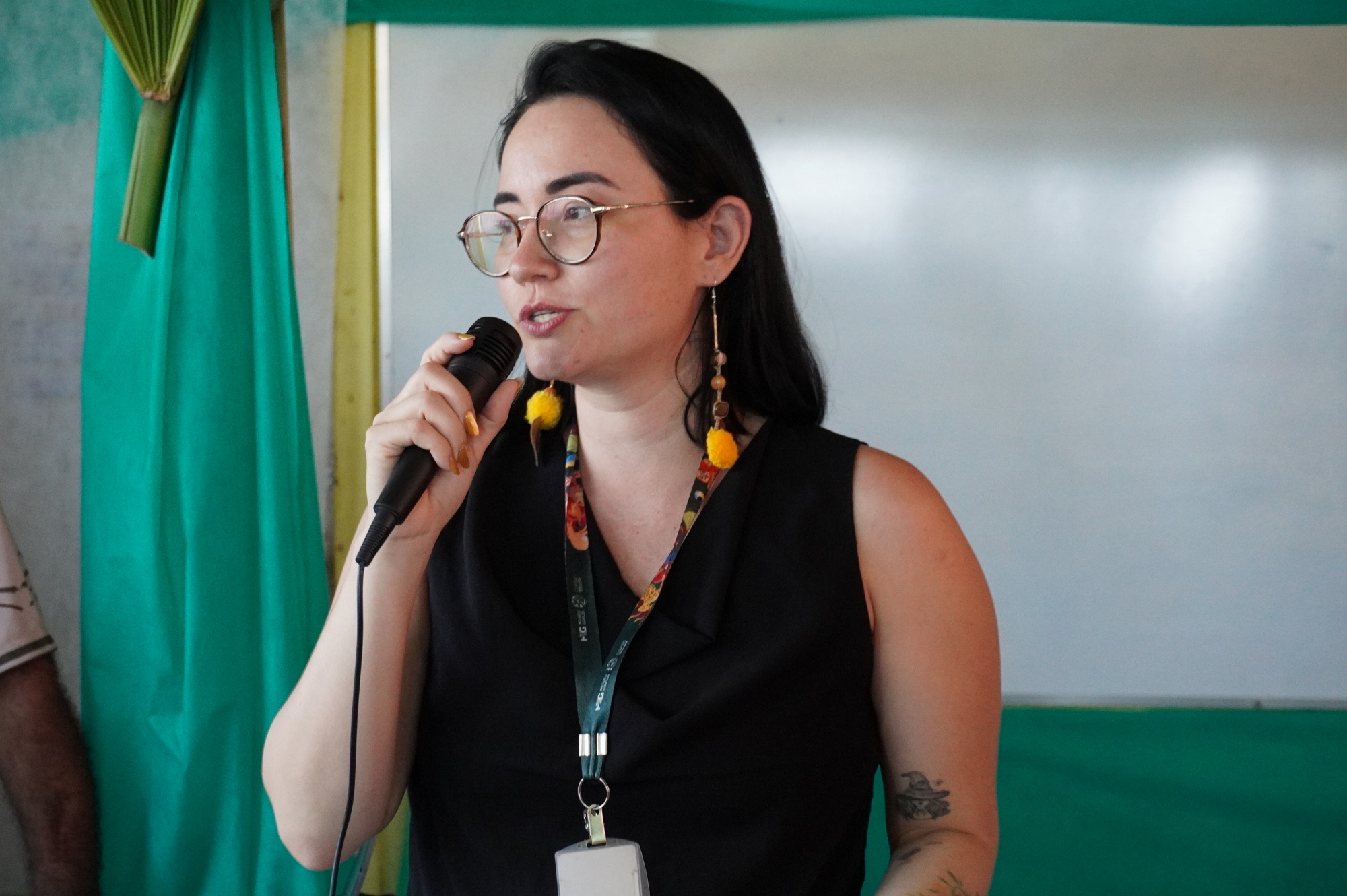 Mulher branca de cabelos lisos fala ao microfone