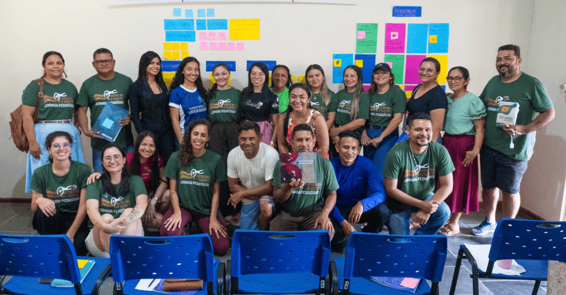 Dois homens estão lado a lado diante de parede com papéis colados durante dinâmica de grupo