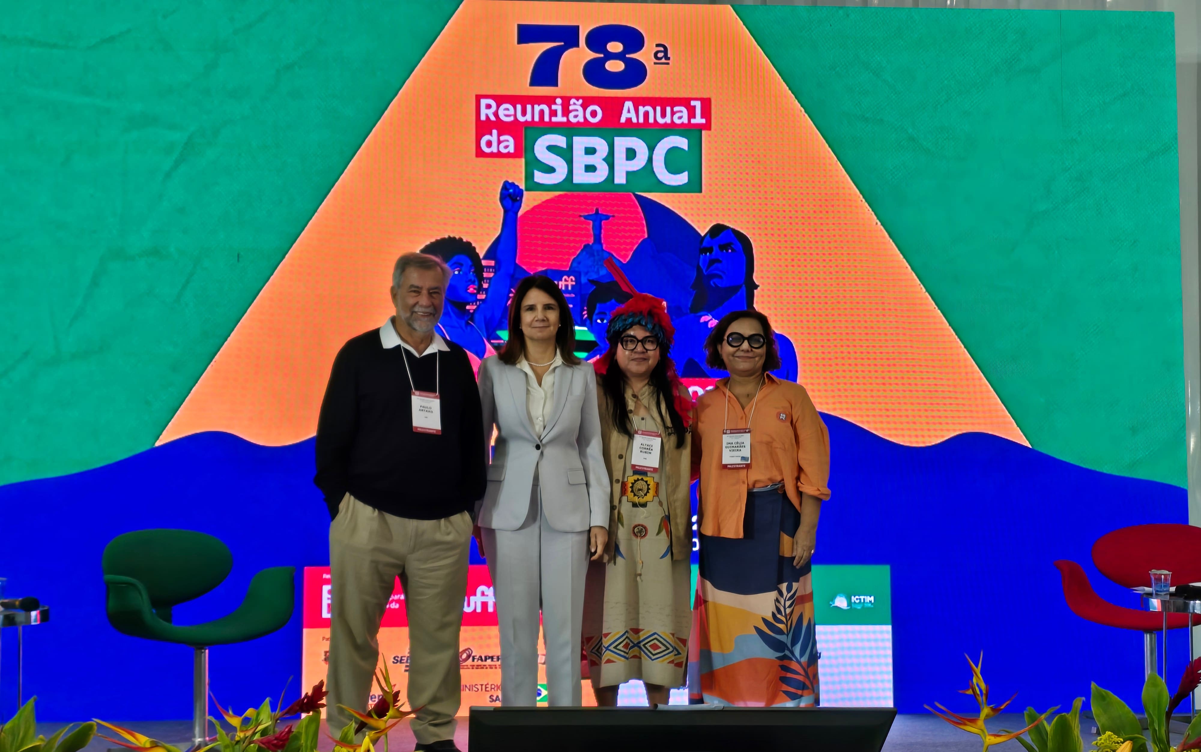 Três mulheres (sendo uma indígena) e um homem posam para foto em frente a painel da SBPC 2026