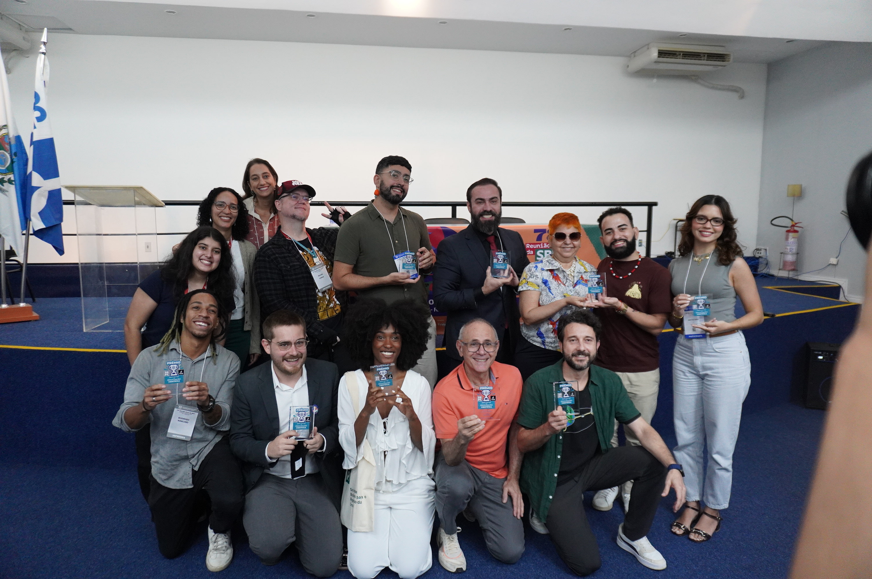 Grupo de pessoas posa para foto segurando troféus