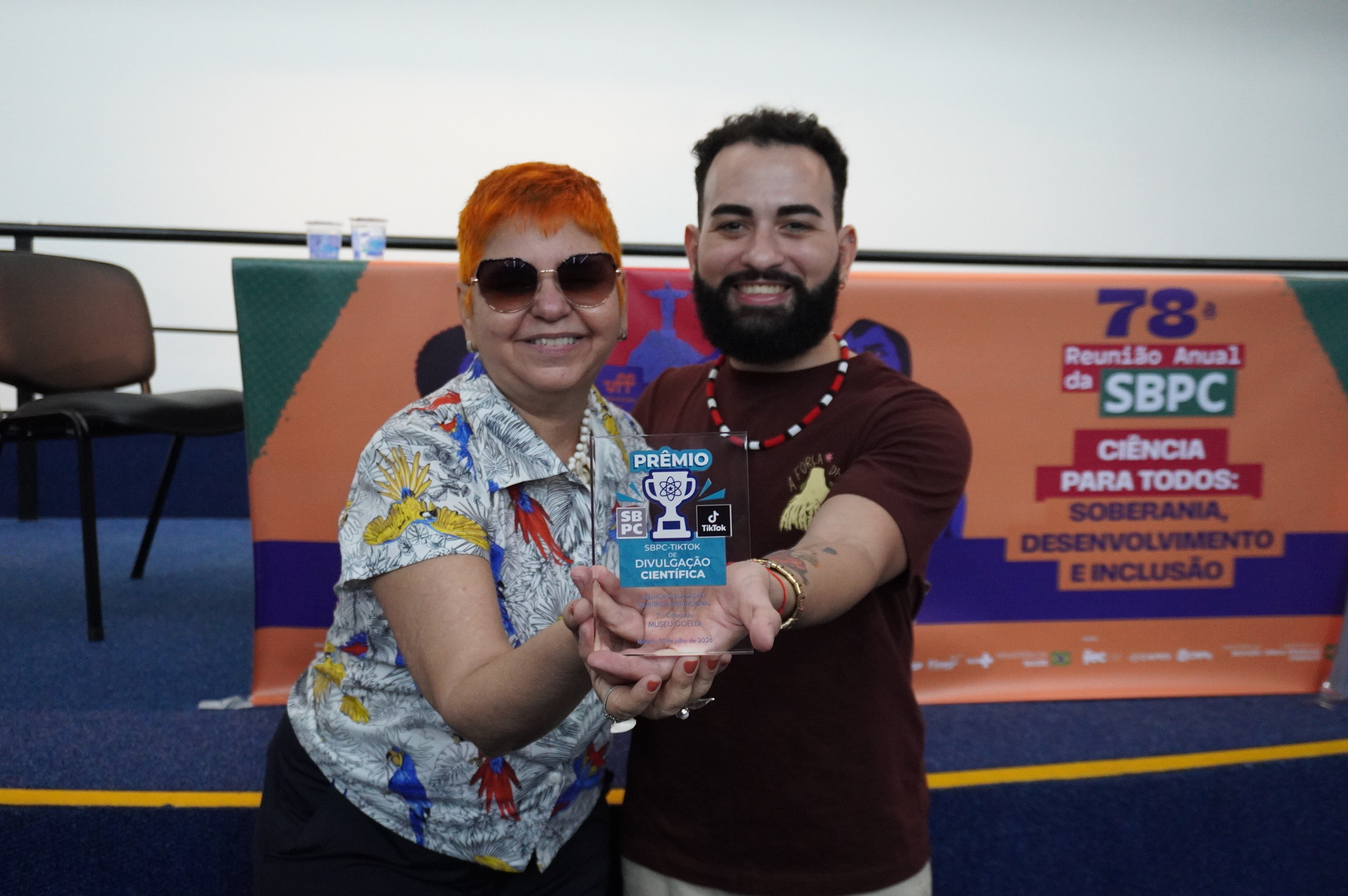 homem e mulher exibem pequeno troféu de acrílico