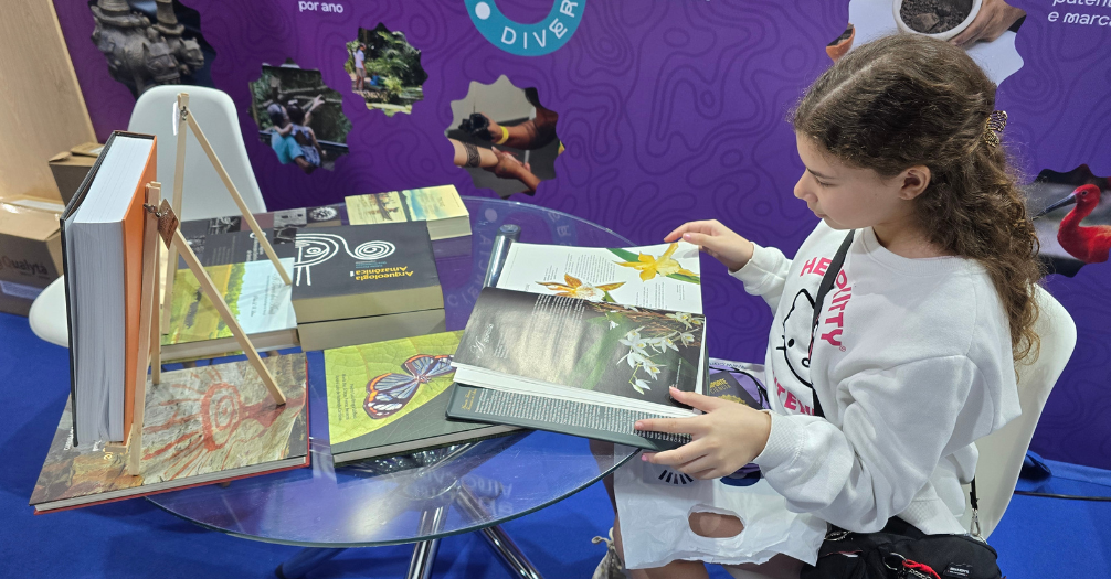 Menina lê livro sobre orquídeas em ambiente montado em estande