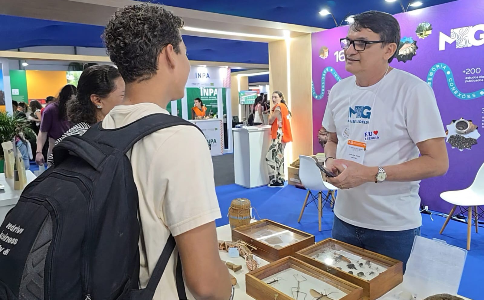 Expositor interage com visitantes em estande