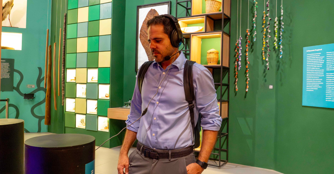 Um homem usa fones de ouvido diante de uma parede verde em exposição sobre a Amazônia