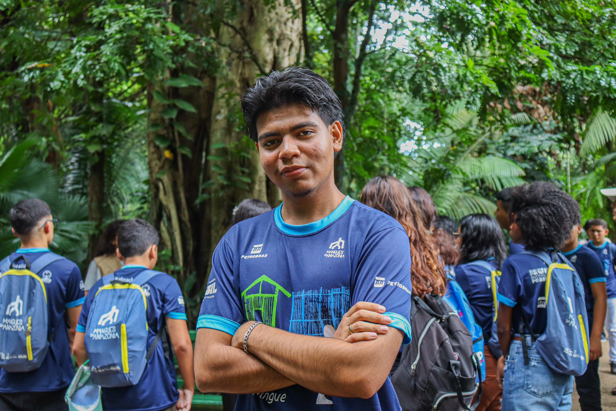 Jovem de cabelos lisos e curtos posa para foto sorrindo e de braços cruzados
