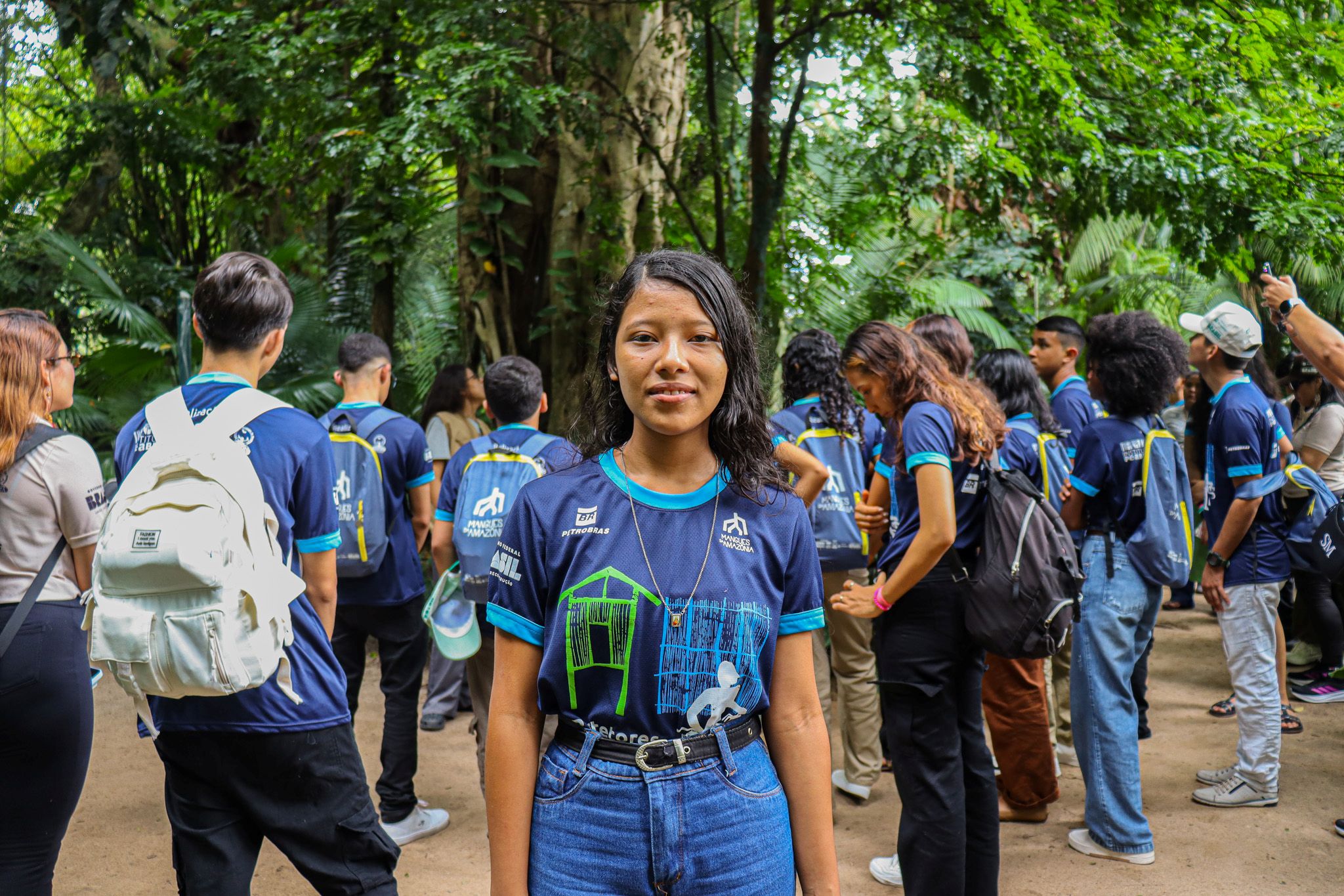 Menina adolescente de cabelos lisos e escuros olha e sorri posando para a fotografia