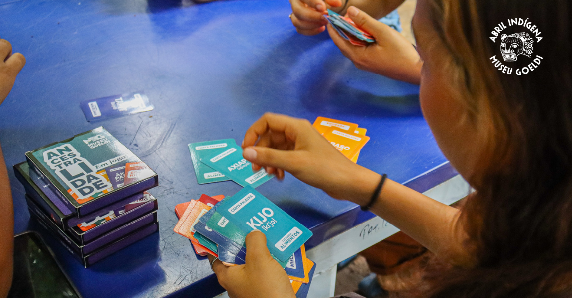 Mãos jovens manuseiam cartas de jogo com palavras indígenas