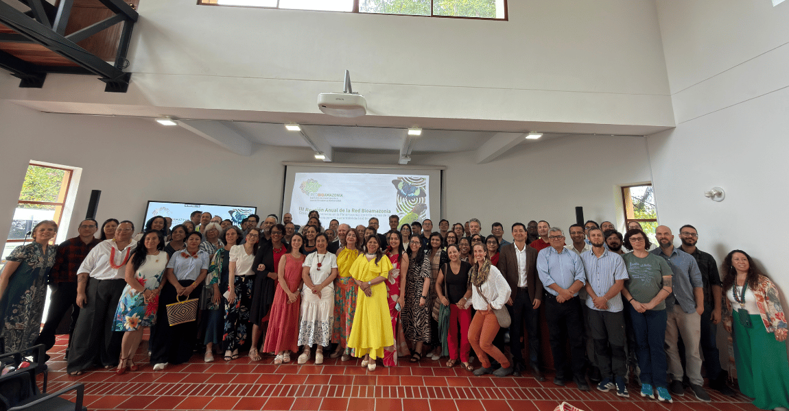 Cinco pessoas, sendo três mulheres e dois homens posam para foto em frente a banner de projeto de bioeconomia