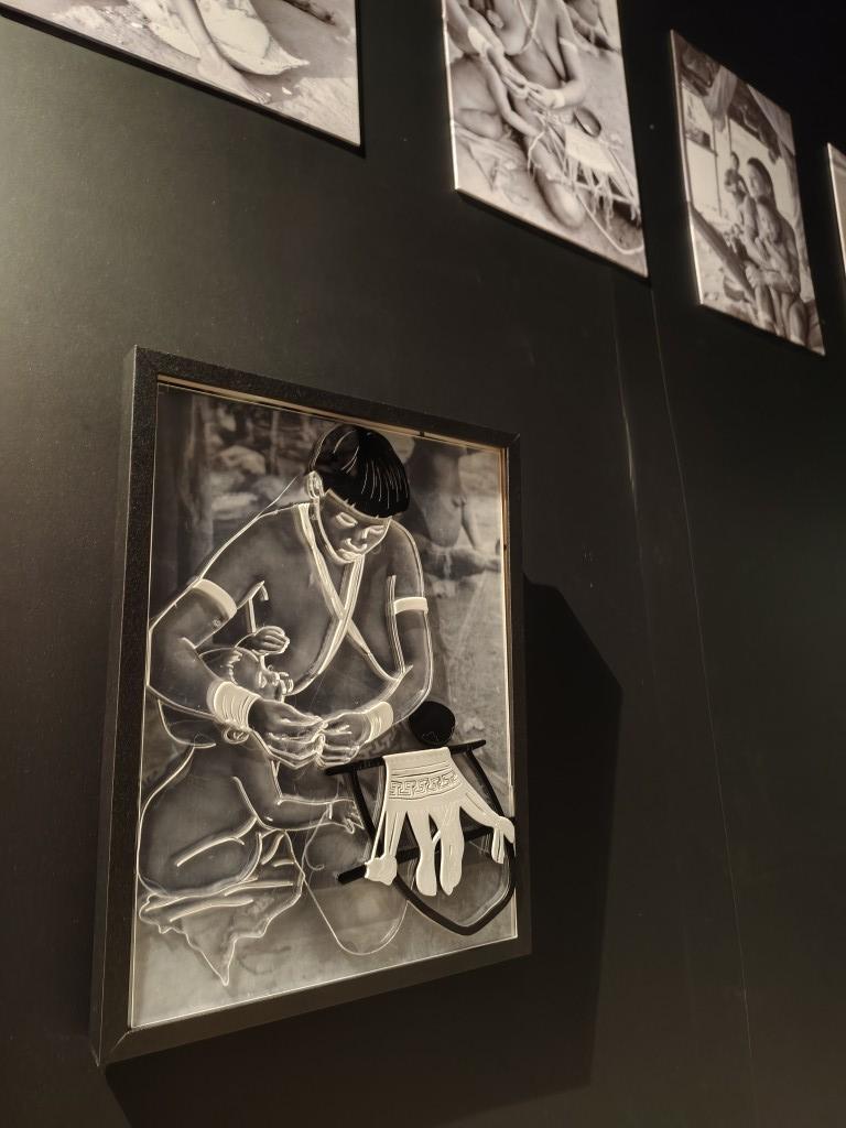 Uma fotografia exposta em alto relevo mostra uma mulher indígena com uma criança