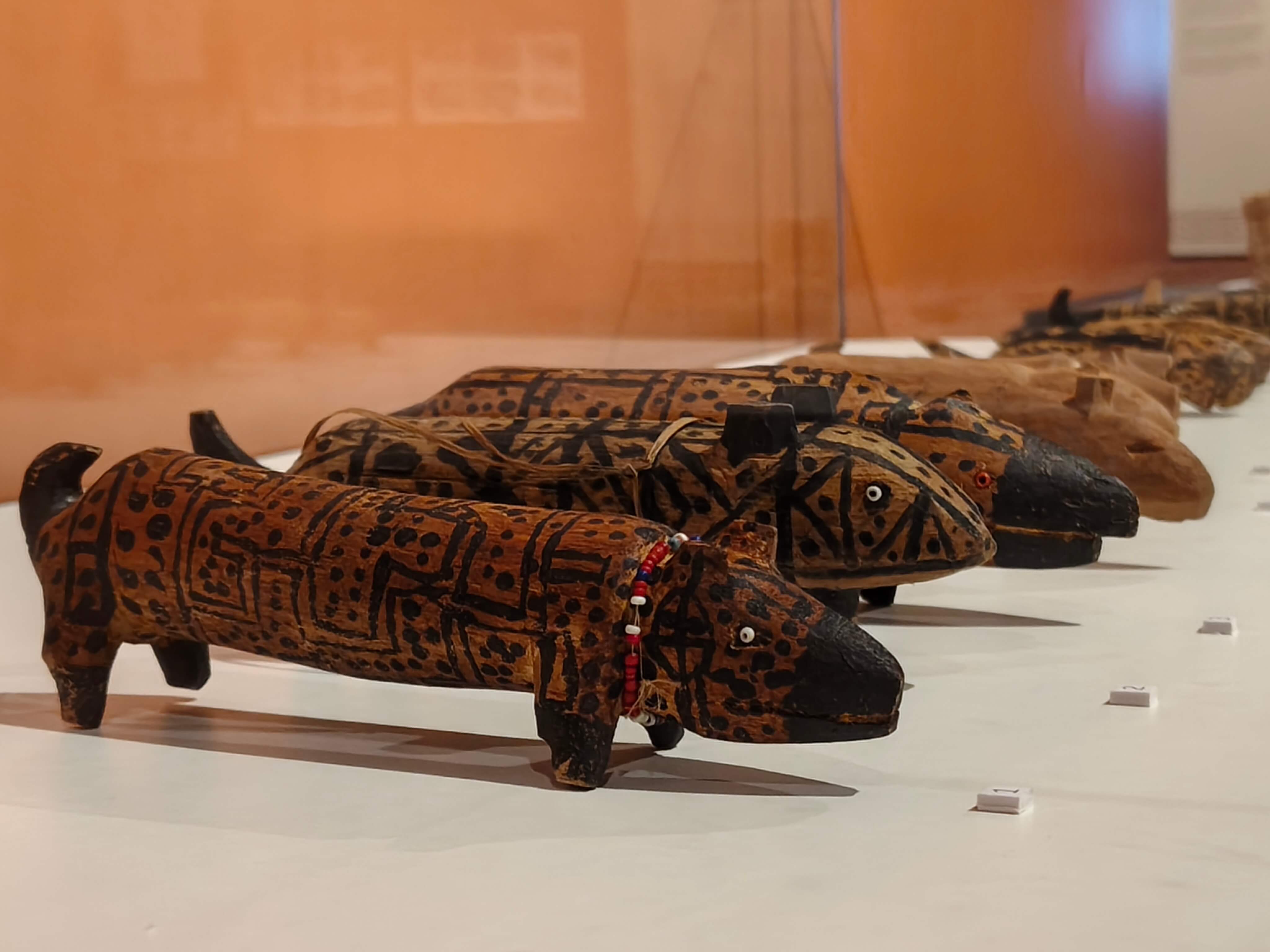 Coleção de pequenos animais de quatro patas em madeira estão expostos numa vitrine