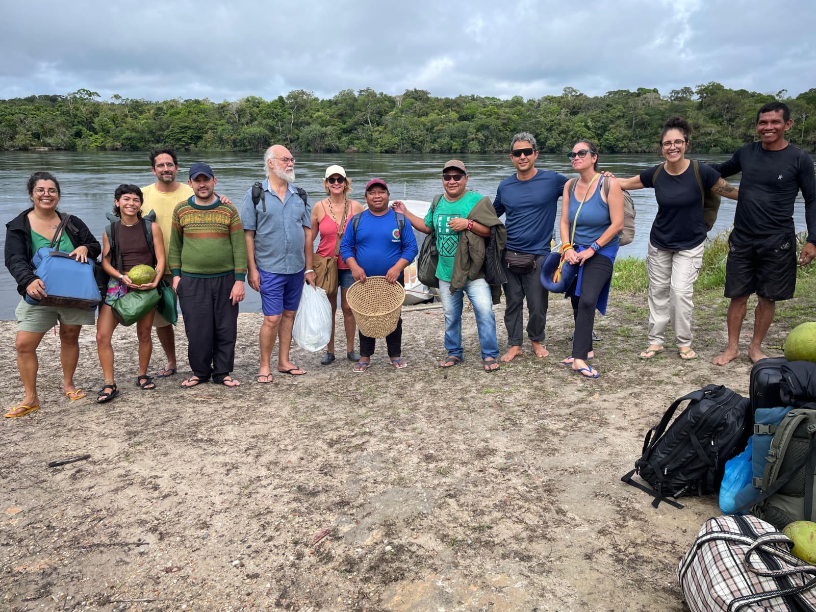 grupo formado por dozes pessoas de raças diversas, entre as quais indígenas, a beira de um rio