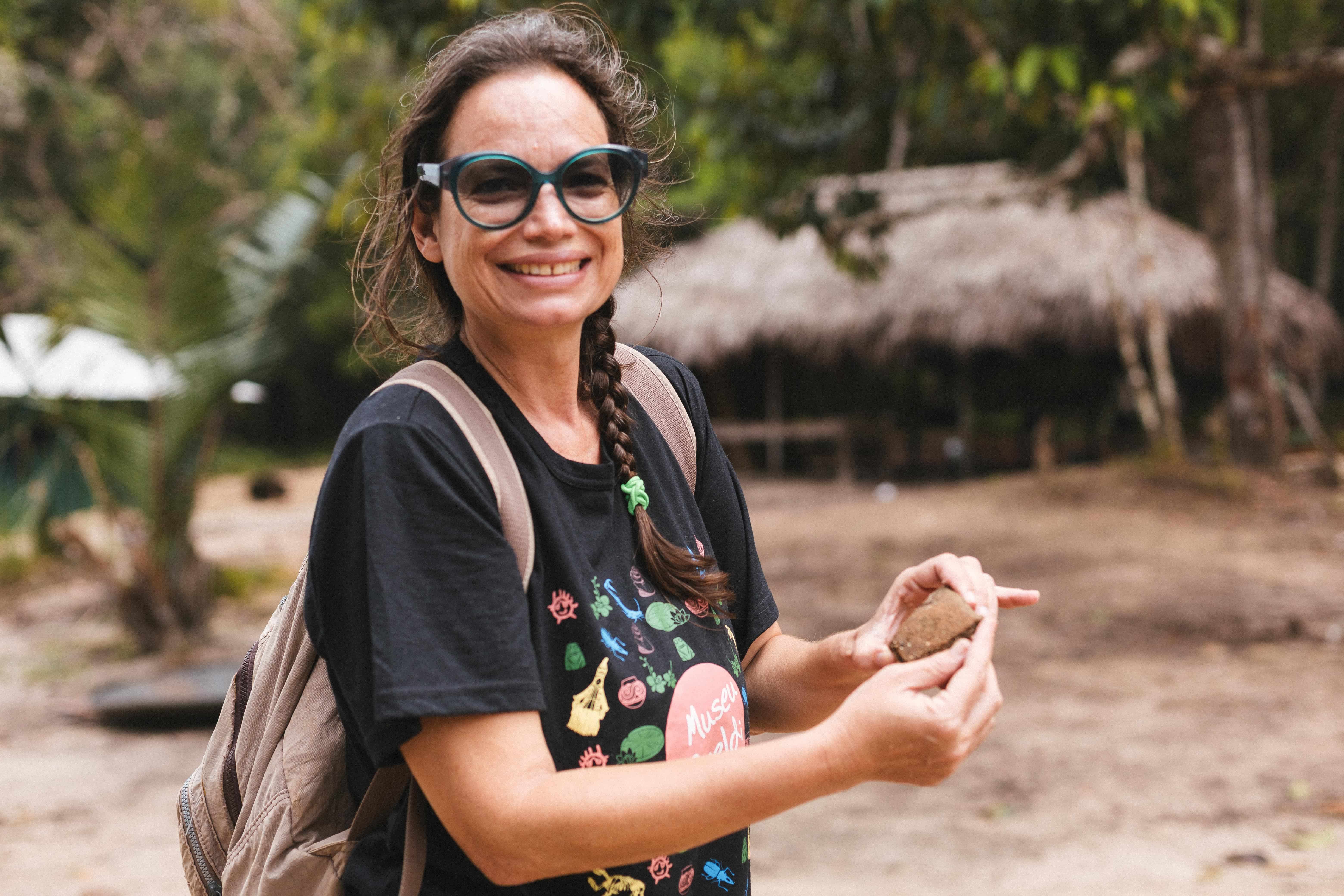 Mulher branca mostra fragmento de cerâmica achada em sítio arqueológico
