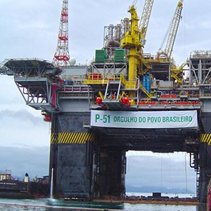 Imagem da galeria de imagem da página de óleo & gás. A imagem mostra uma plataforma de petróleo sendo levada pelo mar com ajuda de rebocadores.