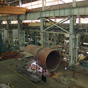 Imagem da galeria de imagem da página de Expertise e Serviços. A imagem mostra equipamentos sendo manuseados no interior de uma grande fábrica.