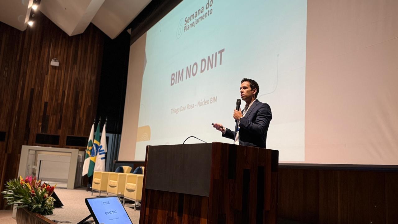 Técnico do DNIT apresentando com slide ao fundo escrito "BIM no DNIT"
