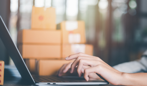 pessoa digitando no computador e caixas ao fundo