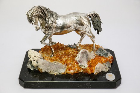 Escultura confeccionada em metal prateado, representando um cavalo