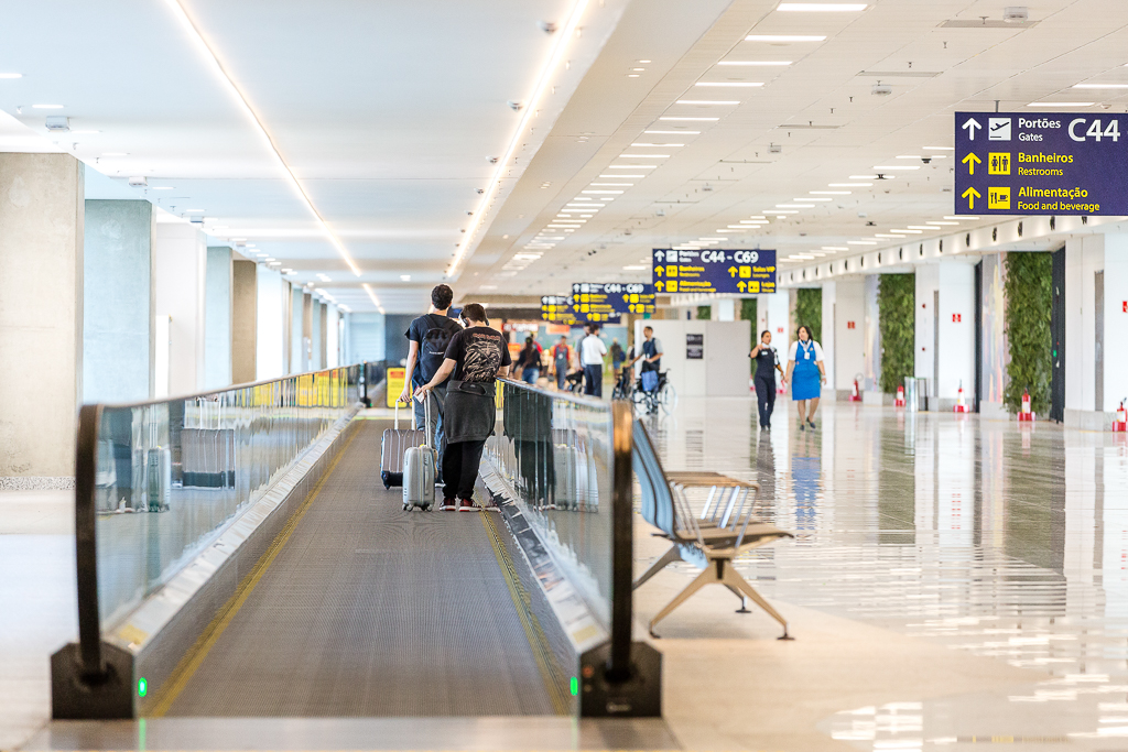 Esteira de aeroporto, onde estão dois jovens com malas