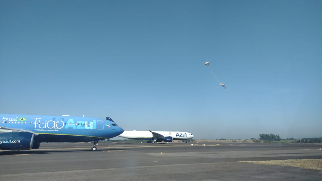 Foto apresenta dois aviões da Azul estacionados ao fundo um balão cai na pista do aeroporto