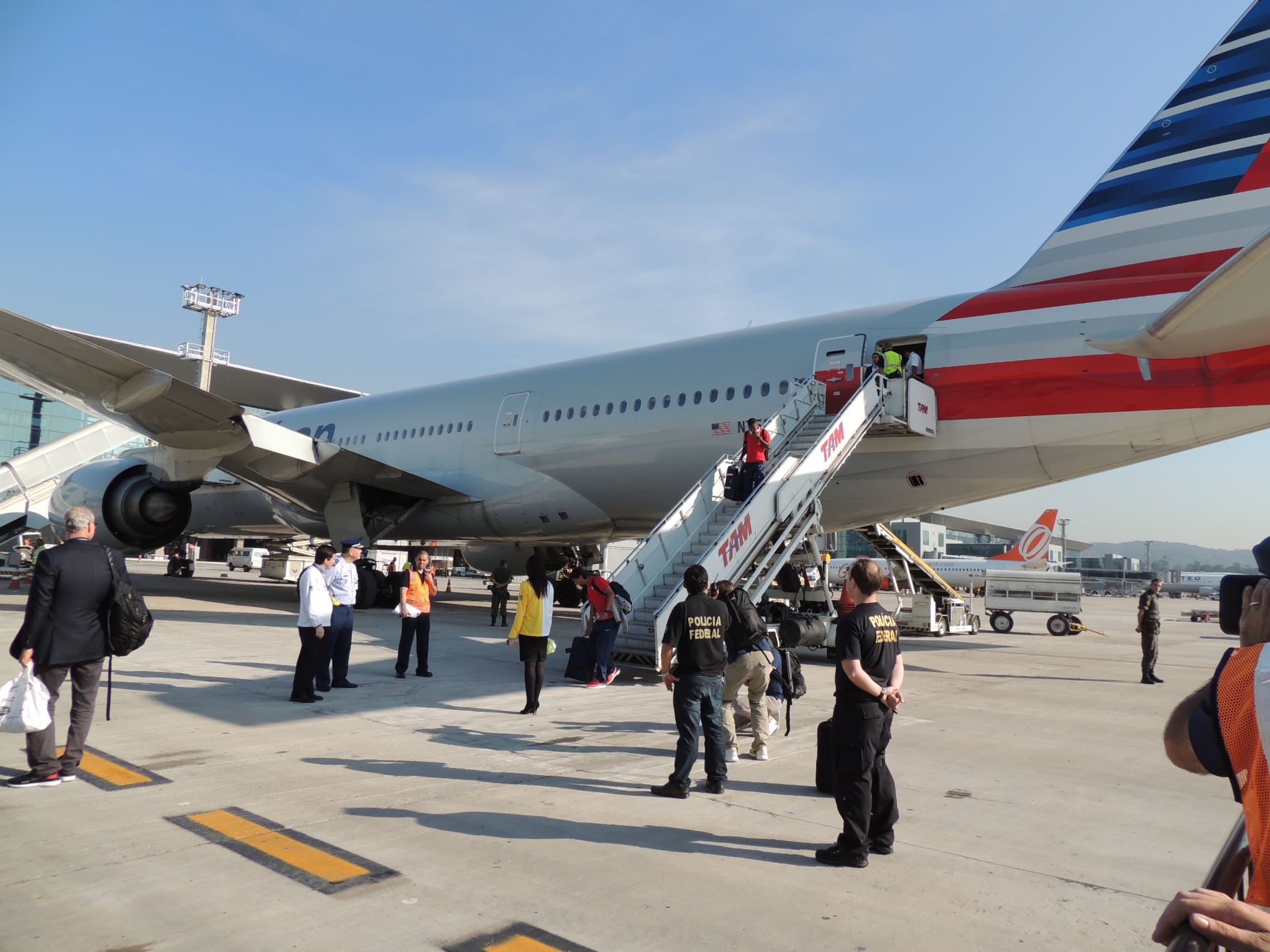 Avião estacionado, com escada na parte traseira, mostra pessoas desembarcando