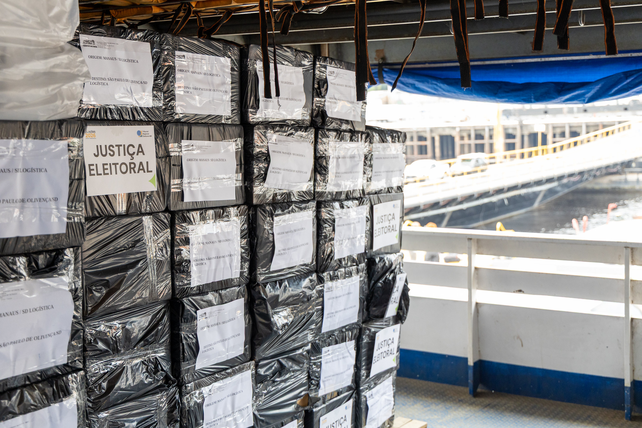 Caixas com materiais da Justiça Eleitoral, embaladas e identificadas, são transportadas em uma embarcação.