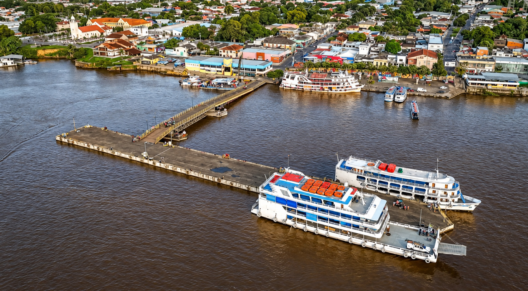 Vista aérea do Porto de Parintins, no Amazonas, com embarcações atracadas, píer flutuante e área urbana ao fundo.
