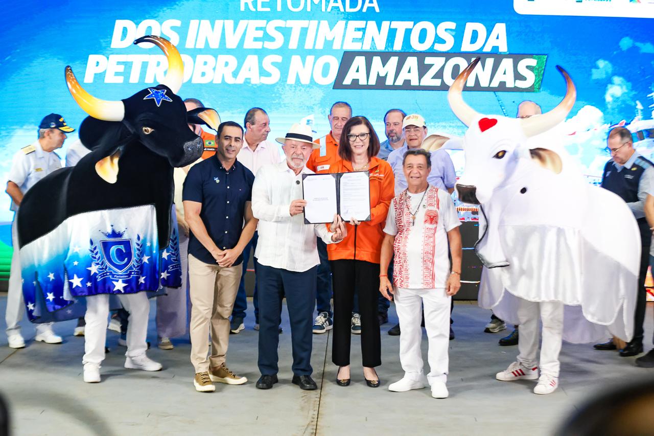 Autoridades reunidas em um palco coberto durante um evento oficial. No centro, vários homens