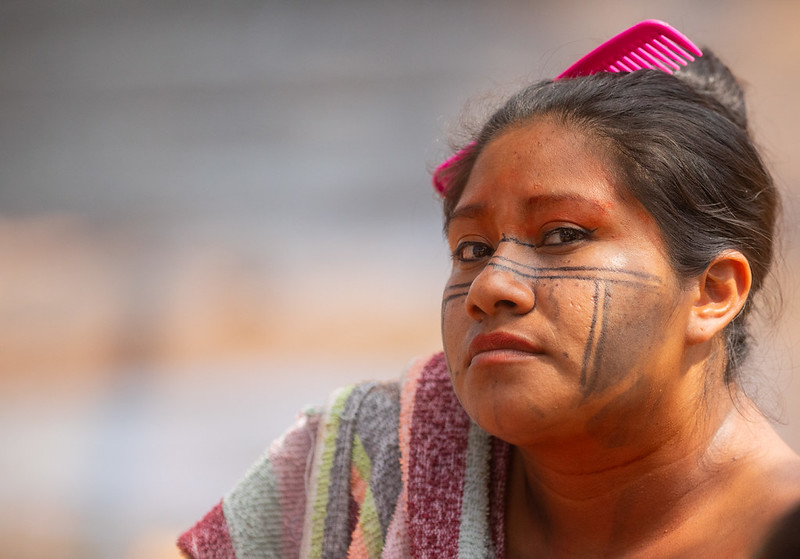 Mulher indígena olha com semblante profundo para a câmera.