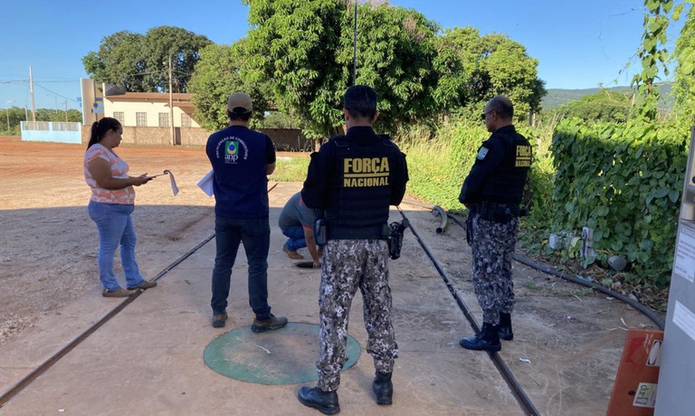 Integrantes de força tarefa se reúnem em torno de uma tanque subterrâneo de gasolina