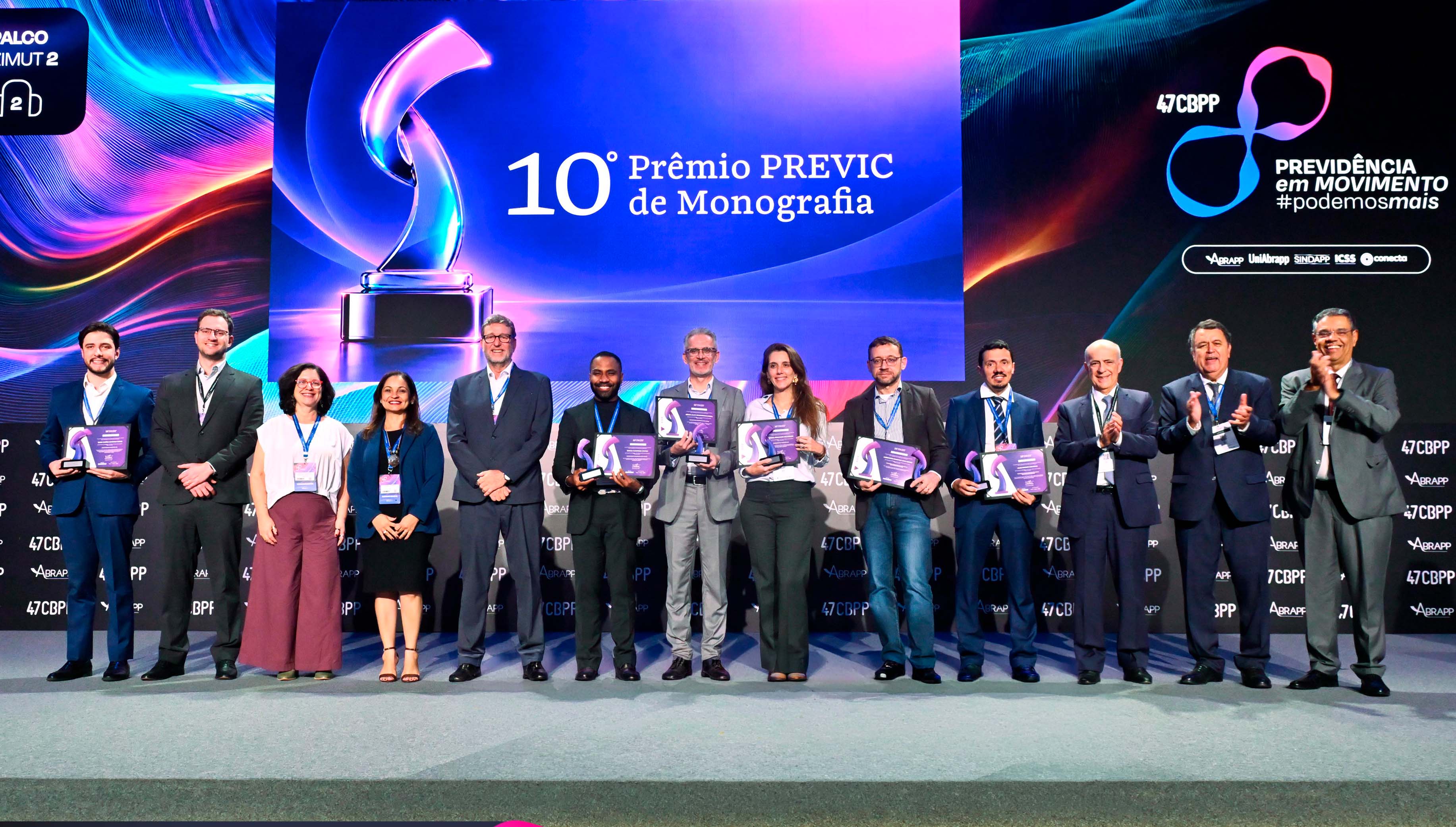 Grupo de premiados e autoridades no palco da cerimônia do 10º Prêmio PREVIC de Monografia