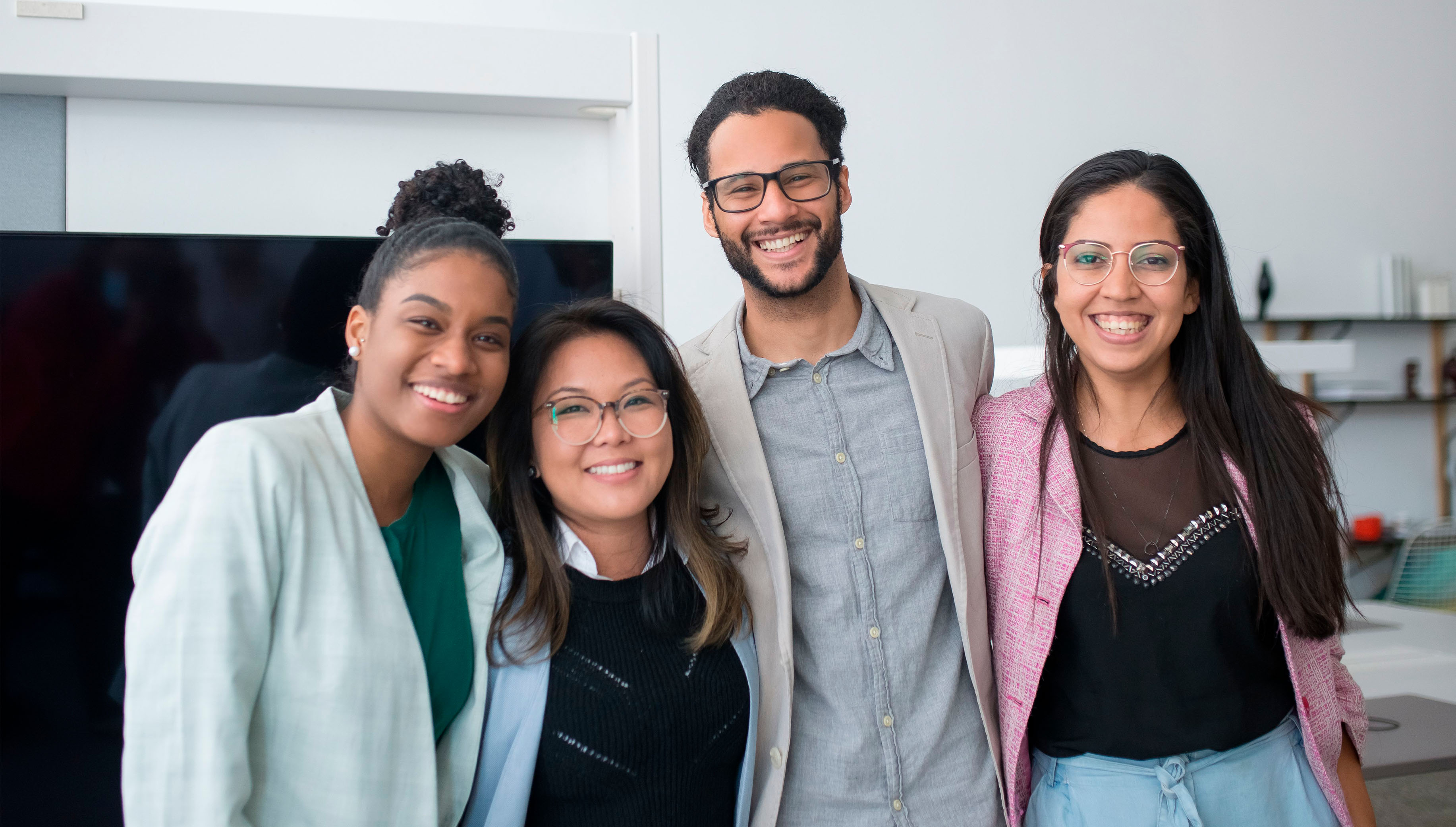 Pessoas sorrindo e se abraçando lado a lado em um ambiente de escritório